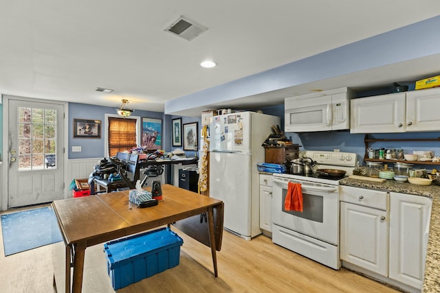 kitchen with white appliances, visible vents, a wainscoted wall, and white cabinetry