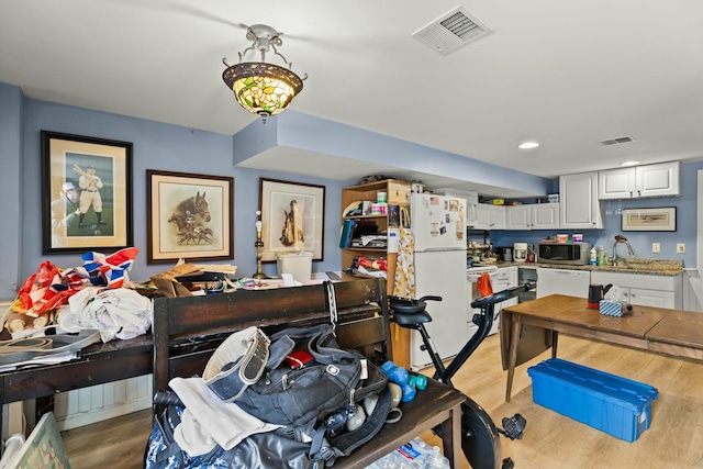 interior space featuring freestanding refrigerator, visible vents, stainless steel microwave, and white cabinetry