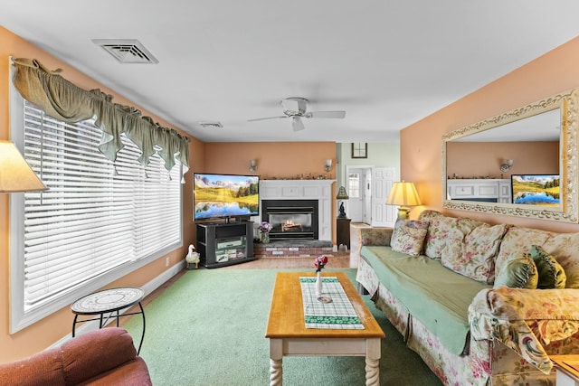 living area with carpet, visible vents, a ceiling fan, and a glass covered fireplace