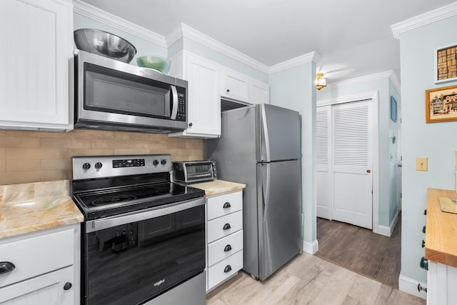 kitchen with decorative backsplash, baseboards, light wood-type flooring, white cabinetry, and stainless steel appliances