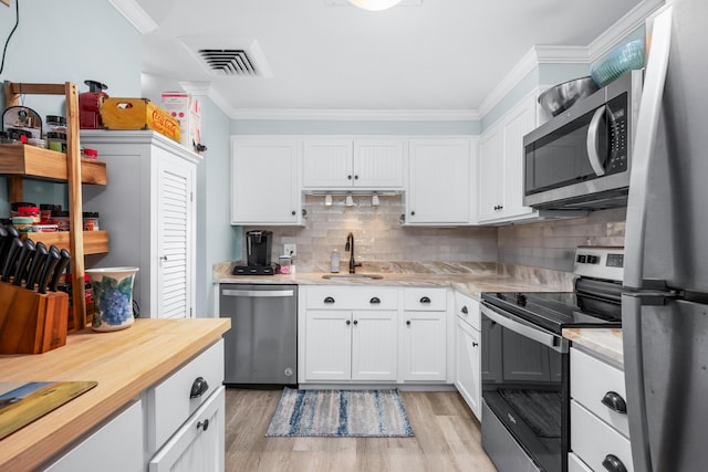 kitchen featuring visible vents, appliances with stainless steel finishes, light wood-type flooring, a sink, and ornamental molding