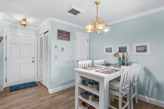 dining space with an inviting chandelier, ornamental molding, baseboards, and wood finished floors