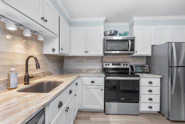 kitchen featuring a sink, crown molding, stainless steel appliances, and white cabinets