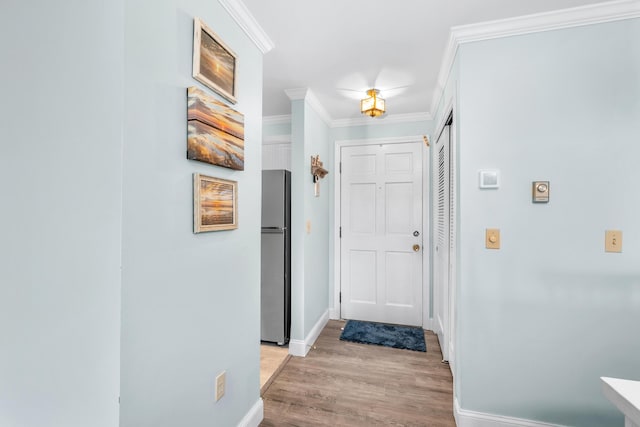 hallway with crown molding, baseboards, and light wood-style flooring