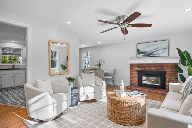 living room featuring sink, a fireplace, hardwood / wood-style floors, and a healthy amount of sunlight