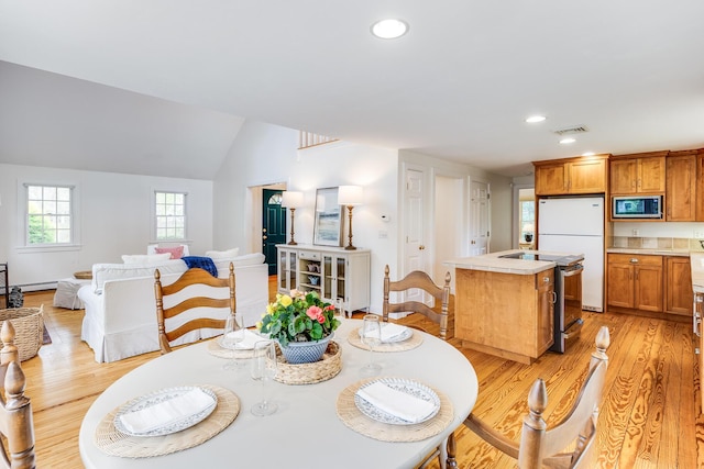 dining space featuring light wood-style flooring, recessed lighting, a baseboard radiator, and lofted ceiling