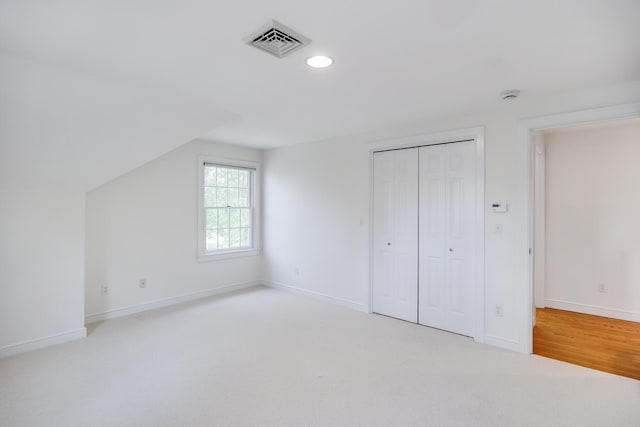 unfurnished bedroom featuring recessed lighting, baseboards, a closet, light carpet, and vaulted ceiling