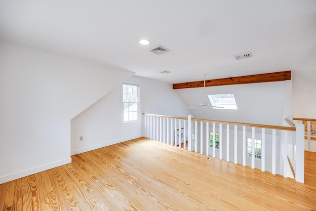 additional living space with lofted ceiling, a skylight, wood finished floors, recessed lighting, and baseboards
