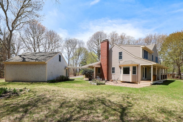 rear view of house featuring covered porch, a lawn, and a chimney