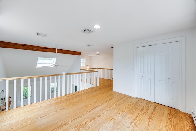 corridor featuring wood finished floors, recessed lighting, a skylight, a baseboard radiator, and beam ceiling