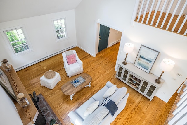 living area with baseboard heating, wood finished floors, and plenty of natural light