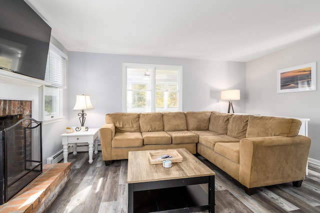 living room with a baseboard radiator, a healthy amount of sunlight, a brick fireplace, and dark hardwood / wood-style flooring