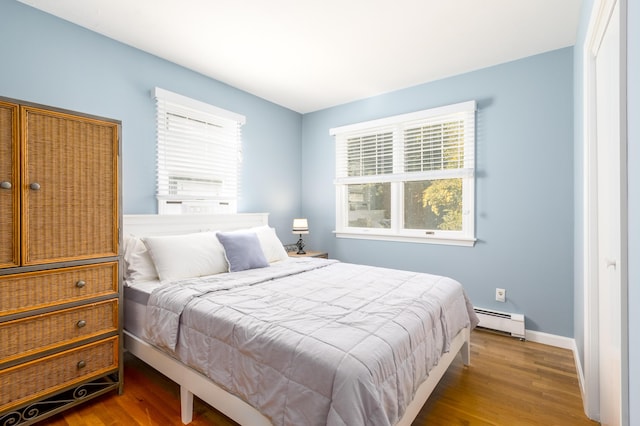 bedroom featuring baseboard heating and hardwood / wood-style flooring