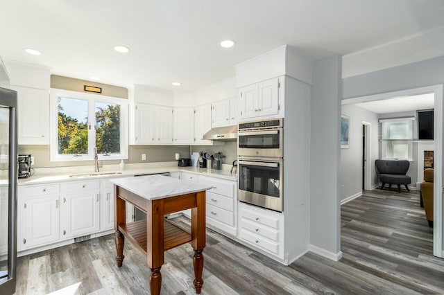 kitchen with white cabinetry, sink, stainless steel double oven, and dark hardwood / wood-style floors