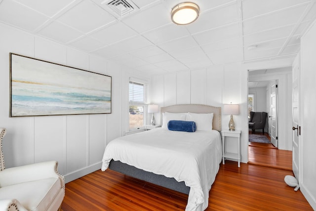 bedroom featuring visible vents, wood finished floors, and a decorative wall