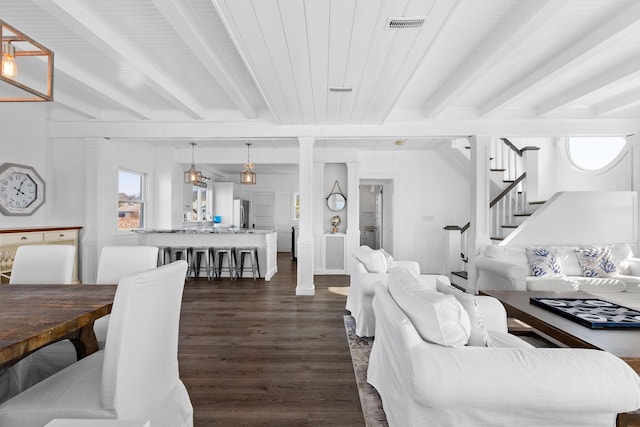 living room featuring dark wood-style floors, beamed ceiling, visible vents, and stairway