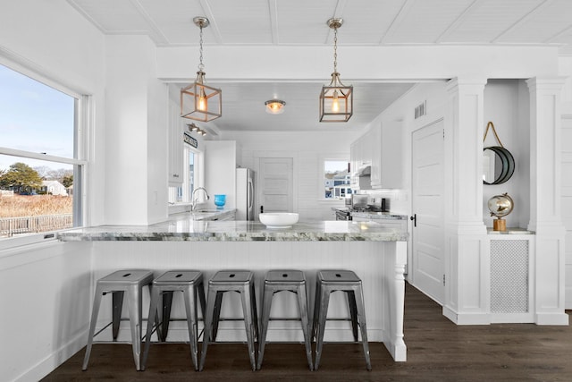 kitchen with stainless steel refrigerator, a peninsula, a sink, and plenty of natural light