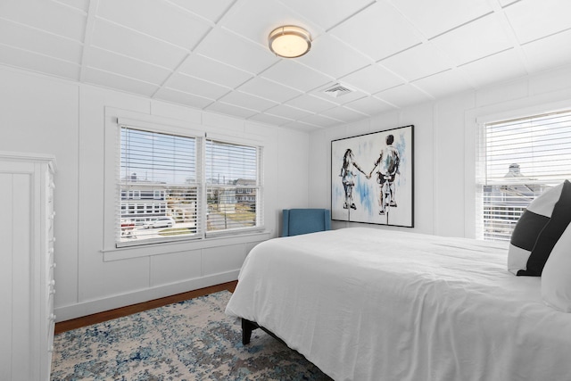 bedroom featuring a drop ceiling, wood finished floors, multiple windows, and visible vents
