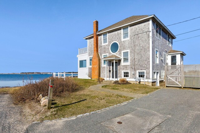 shingle-style home featuring a chimney and a water view