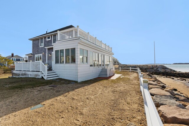 view of property exterior with a balcony, a water view, and fence