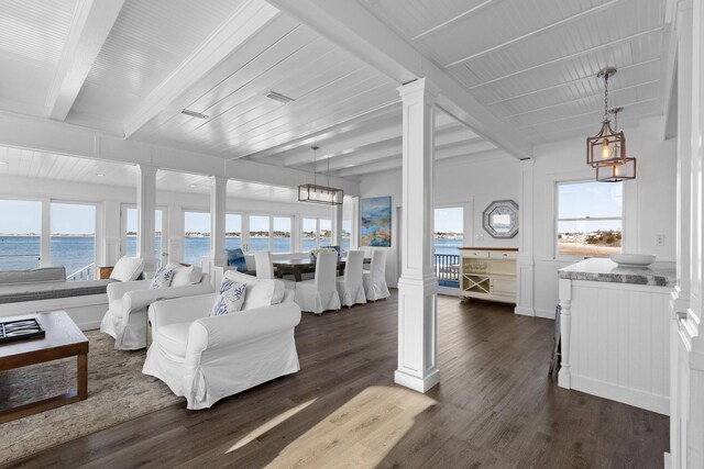 living area featuring ornate columns, dark wood finished floors, a water view, and beam ceiling
