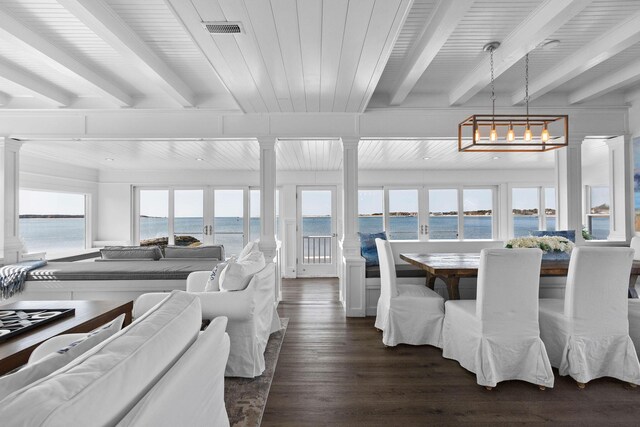 dining area with ornate columns, a water view, visible vents, and beam ceiling