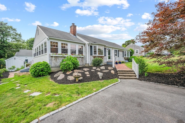 69 Joan Rd, Centerville, MA 02632 - view of front of house featuring a chimney, a front lawn, and a shingled roof