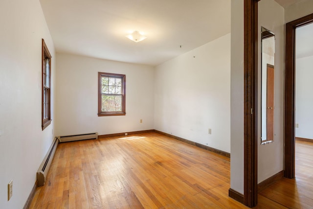 spare room with light wood-style flooring, a baseboard heating unit, baseboard heating, and baseboards