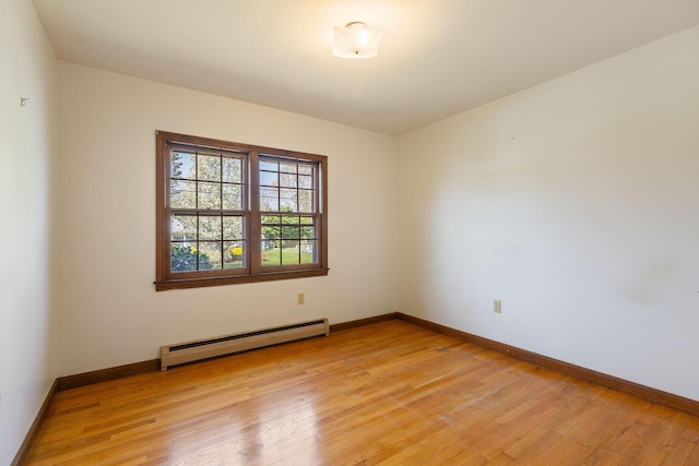 empty room featuring a baseboard radiator, light wood-style floors, and baseboards