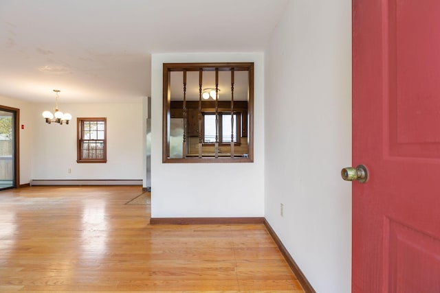 entrance foyer featuring a baseboard heating unit, a chandelier, light wood-style flooring, and baseboards