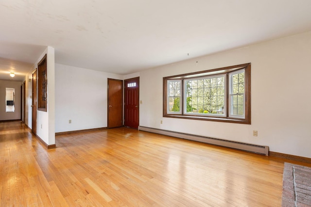 unfurnished living room featuring a baseboard heating unit, light wood-style floors, and baseboards