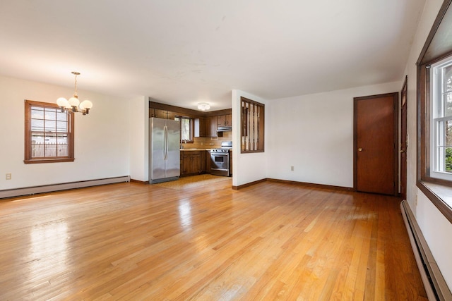 unfurnished living room with baseboard heating, a chandelier, and light wood-style flooring