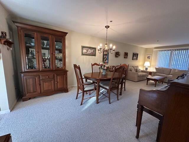 dining room with an inviting chandelier and light carpet