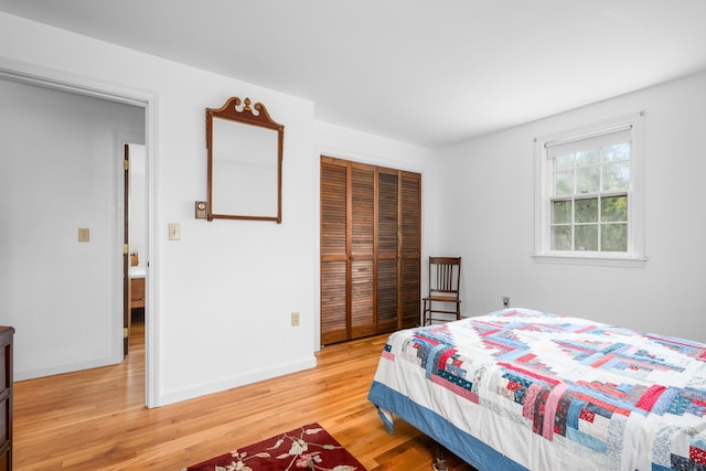 bedroom featuring light wood-type flooring, a closet, and baseboards