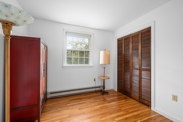 bedroom with a baseboard radiator, a closet, and light wood-type flooring