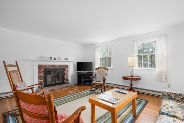 living room with baseboard heating, wood finished floors, and a brick fireplace