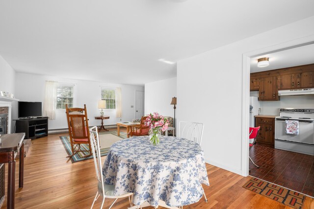 dining space with a baseboard heating unit and light wood-type flooring