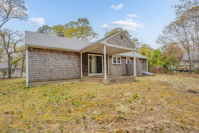 back of house with a patio, a chimney, and a shingled roof