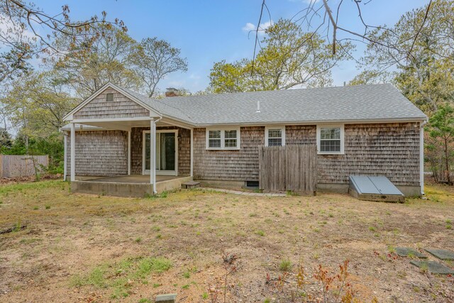 back of property with a patio area, roof with shingles, a chimney, and fence