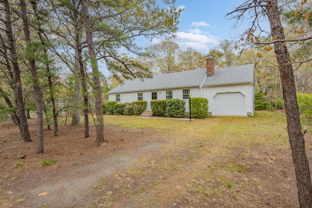 view of front of home featuring a garage, a chimney, a shingled roof, and driveway