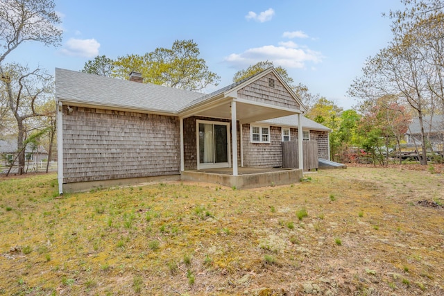 back of house with a patio, a chimney, and a shingled roof