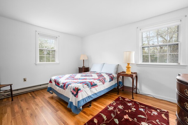bedroom featuring a baseboard heating unit and wood finished floors