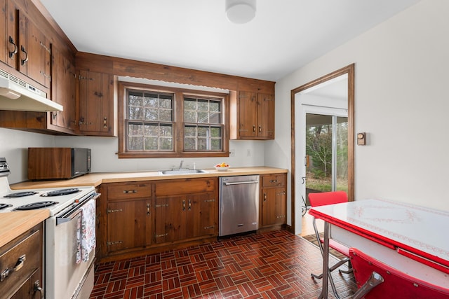 kitchen with white electric stove, stainless steel dishwasher, a sink, brick patterned floors, and light countertops