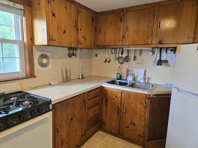 22 Cypress St, East Falmouth, MA 02536 - kitchen featuring range with gas stovetop, freestanding refrigerator, a sink, brown cabinetry, and healthy amount of natural light
