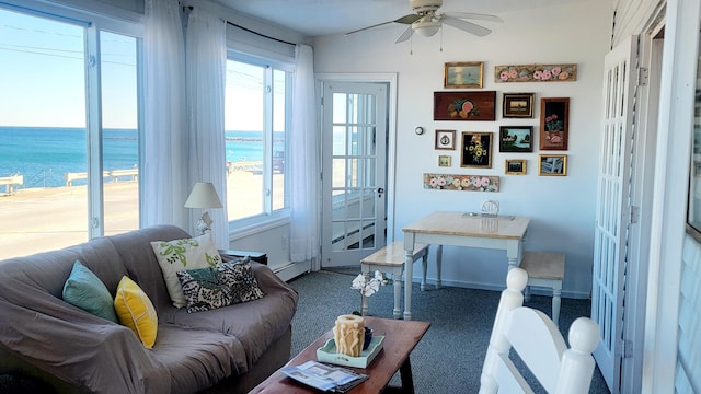 living room featuring ceiling fan and a water view