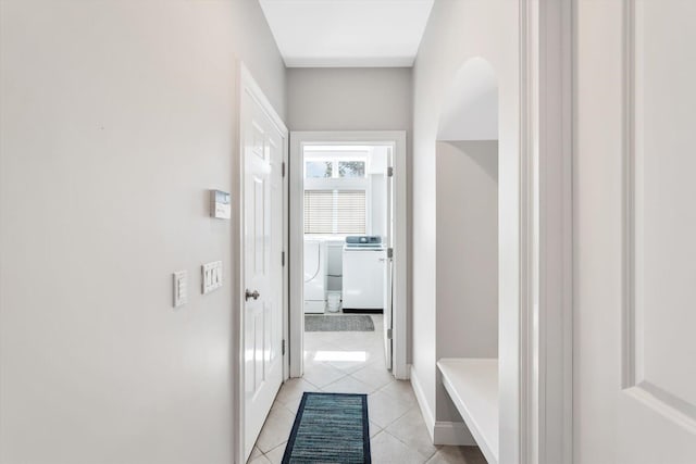 interior space featuring baseboards, light tile patterned flooring, and washing machine and clothes dryer