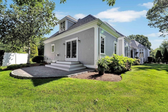 rear view of house with entry steps, a patio area, fence, and a yard