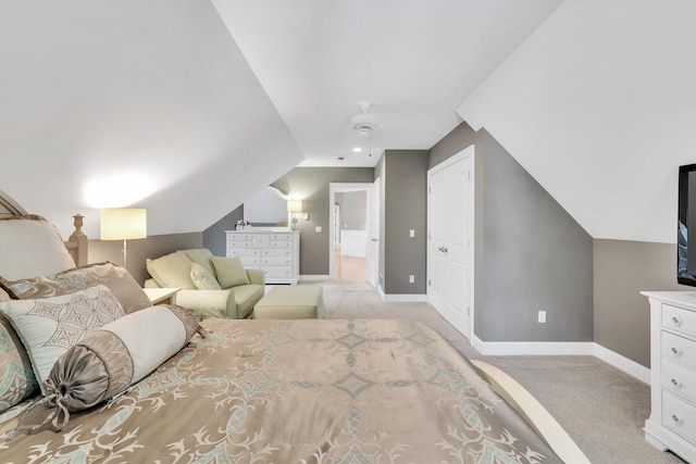 bedroom featuring light carpet, baseboards, ensuite bathroom, and lofted ceiling