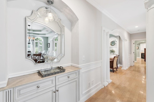 hall featuring arched walkways, light wood-style flooring, recessed lighting, ornamental molding, and ornate columns