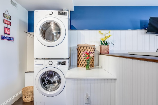 laundry room featuring stacked washer / drying machine and wood finished floors